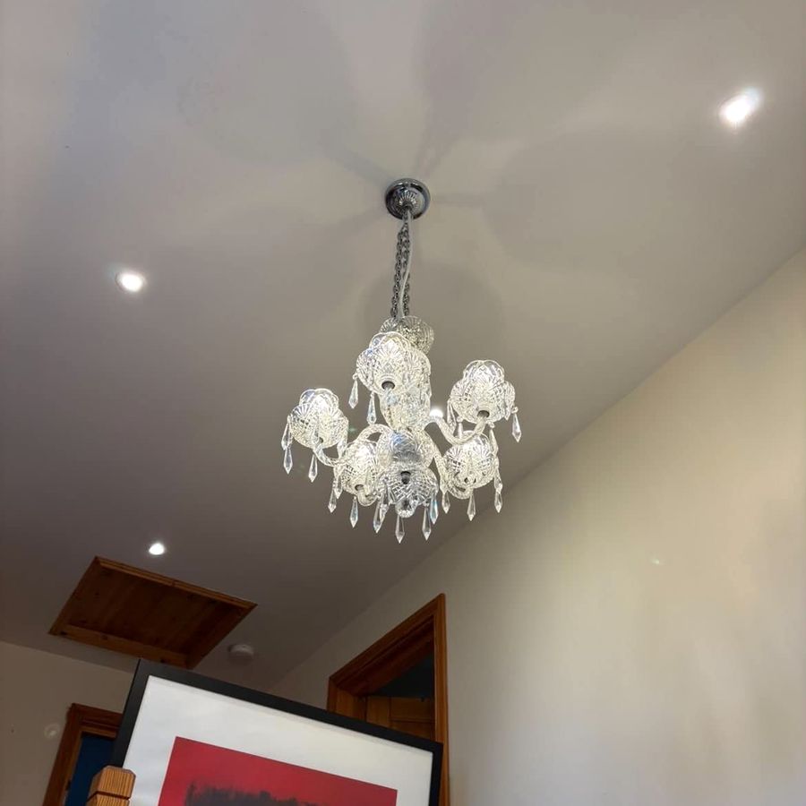 A cut glass chandelier hanging in the same stairwell, catching the light