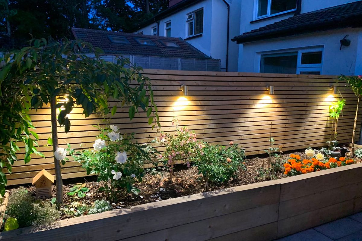 Slatted-fence downlights on a Dublin patio, lit at dusk