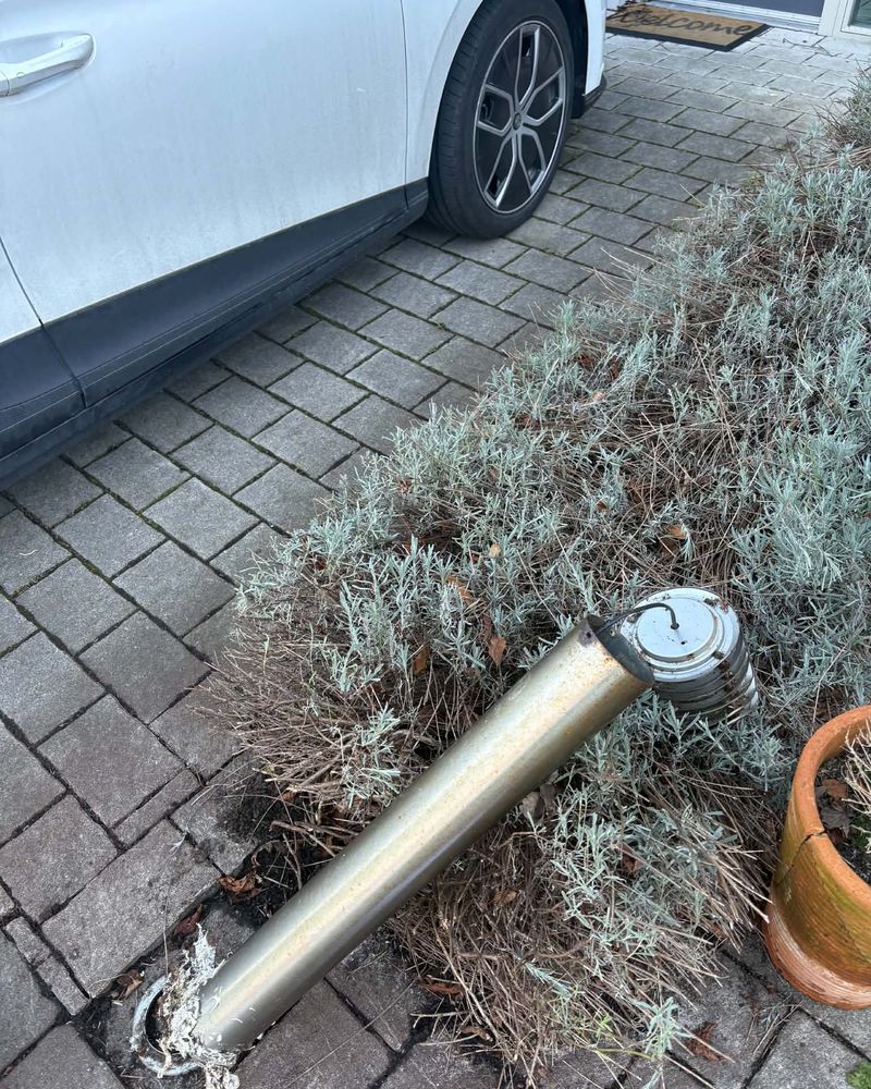 The old corroded bollard light lying on the driveway after removal