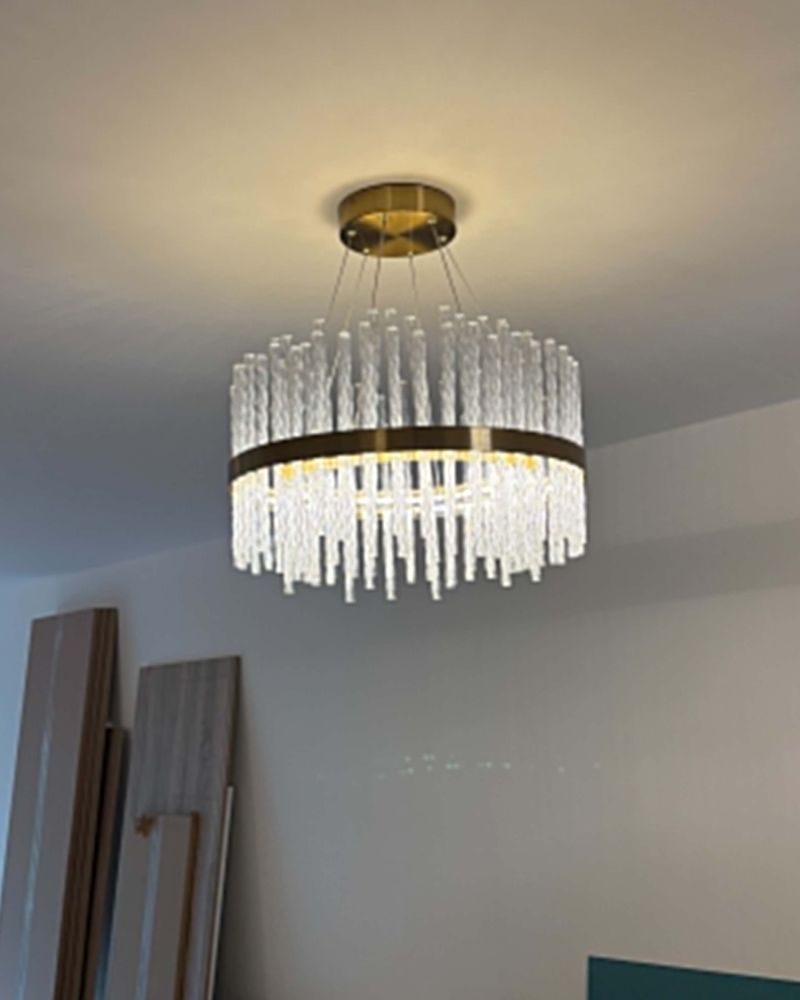 A crystal and brass drum chandelier lit on a bedroom ceiling