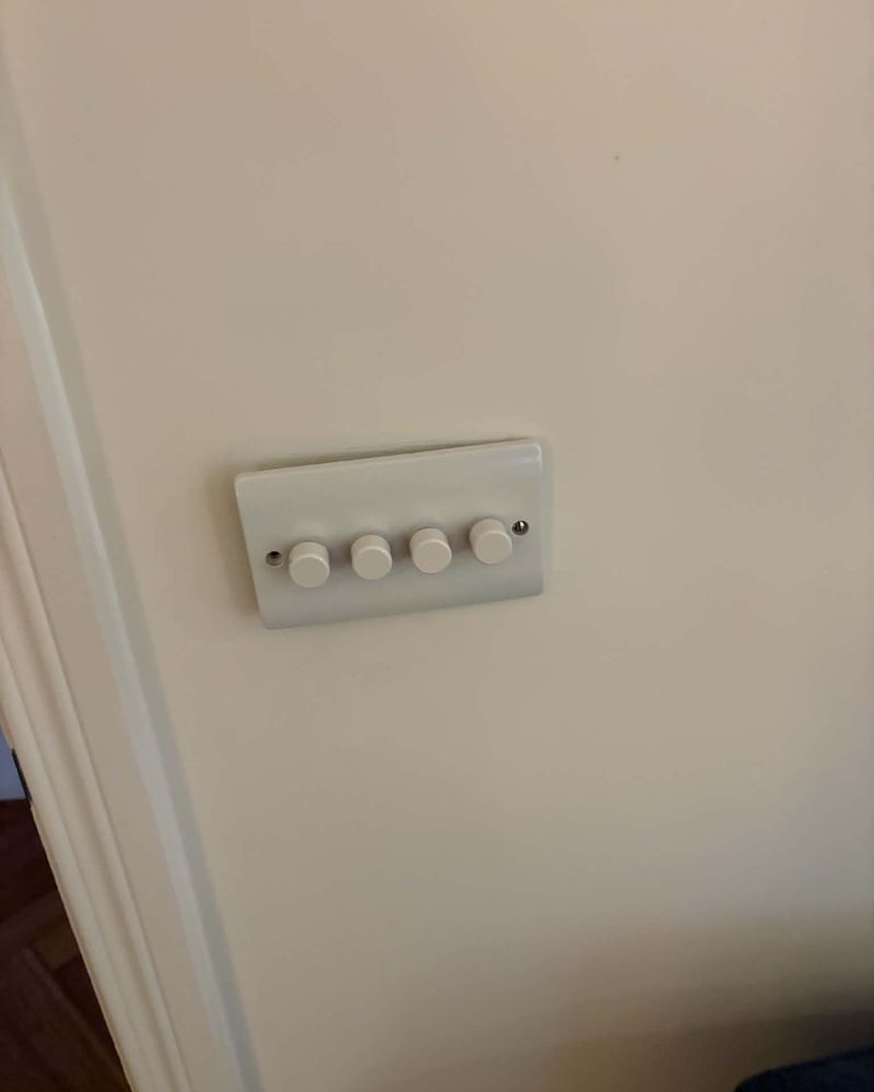A four-gang dimmer plate fitted to a hallway wall