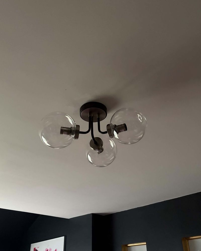 A three-globe black ceiling fitting with clear glass shades